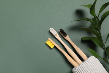 Toothbrushes and fresh leaves on green background, flat lay