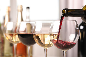 Pouring red wine from bottle into glass, closeup
