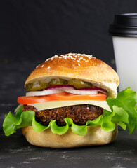 Cheeseburgers and cup of coffee on a black stone background. Hamburger with cheese. Burger isolated. Tasty Dinner.Copy space
