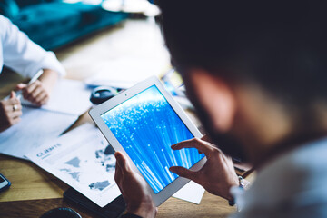 Cropped male user connecting to 4g wireless internet for making online booking during collaborative meeting for brainstorming on project, man checking received notification on modern touch pad