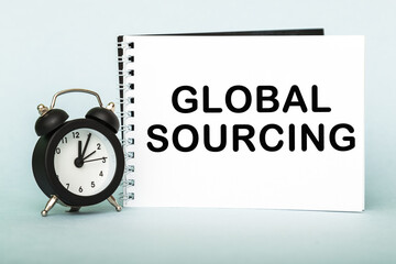 A words GLOBAL SOURCING on notebook with clock. Concept for time management and business.