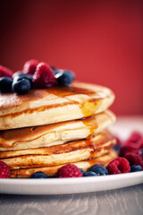 Pancakes with berries and maple syrup on a plate.