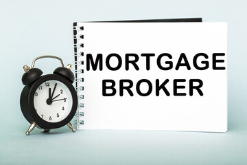 A words MORTGAGE BROKER on notebook with clock. Concept for time management and business.