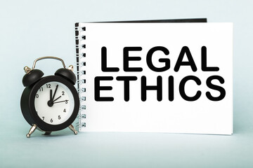 A words LEGAL ETHICS on notebook with clock. Concept for time management and business.