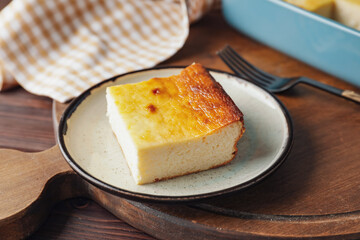Plate with piece of cottage cheese casserole on wooden background