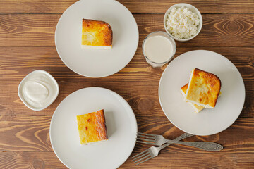 Plates with pieces of cottage cheese casserole on wooden background