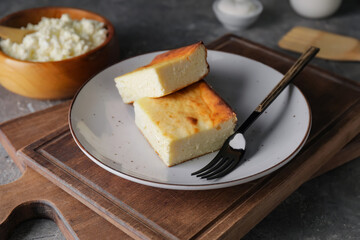 Plate with pieces of cottage cheese casserole on grunge background
