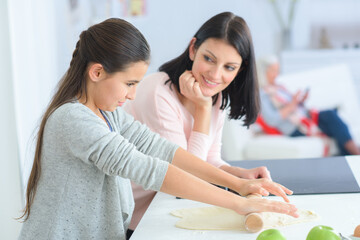 mother teaching her daughter to roll dough