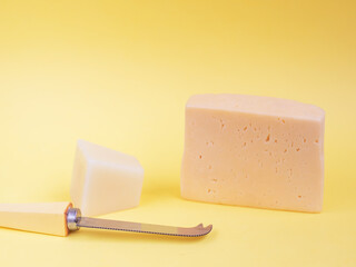 pieces of fresh cheese and knife on a yellow background