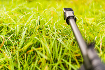 Aiming a rifle in the grass covered with morning dew. Close up view from ground level, focus on the...