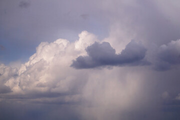 Naklejka na ściany i meble A sky with many clouds, from light and white, illuminated by the sun, to dark thunderclouds.