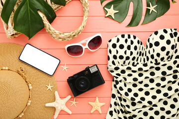 Fashion swimsuit with starfishes, monstera leafs, sunglasses, straw hat and retro camera on wooden table