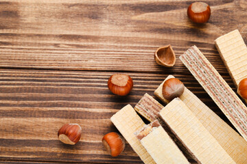 Wafer sticks with hazelnuts on brown wooden background