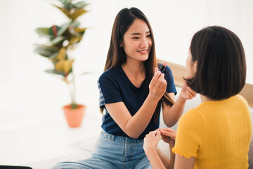 Young beautiful Asian couple love friend woman talking and make up online learning by notebook on bed at home which smiling and felling happy, LGBT woman love Travelling summer vacation trip concept.