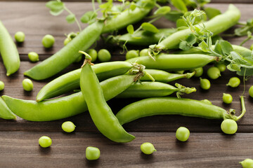 Green pea pods on brown wooden table