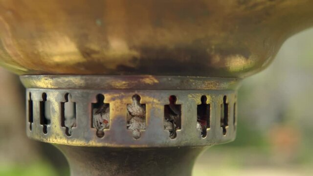 Firewood is burning in the firebox of a brass samo