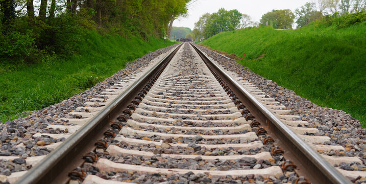 Railroad tracks in the countryside. Landscape with a straight railroad. A single track. The railroad ties (crossties, railway sleepers) are made of concrete. 