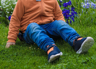 kleiner Junge, der auf grünem Gras sitzt