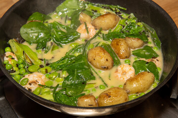 A delicious plate of potatoes fricassee with tiger prawns boiling and cooking in a pan