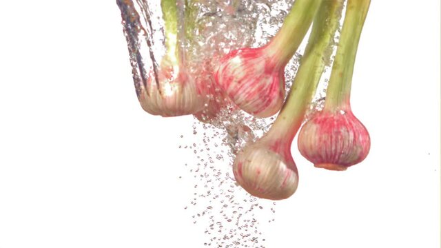 Super slow motion garlic falls under the water with air. On a white background. Filmed on a high-speed camera at 1000 fps.High quality FullHD footage