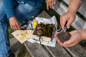 close up view of two caucasian women shucking raw oysters and enjoying them with lemon