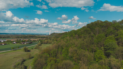 Landschaft in Deutschland mit Waldstück am Hang und Atomkraftwerk