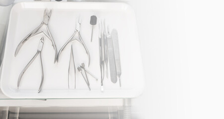 Medical instruments on a white tray with white copy space at the right. Chiropody tools. Nail nippers and nail rasps.