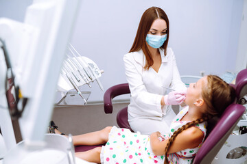 Little girl visiting dentists. Pretty girl opening his mouth wide during treating her teeth by the dentist.  Early prevention, oral hygiene and milk teeth care.