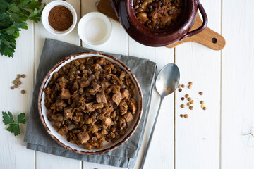 A hearty lunch: stewed lentils with meat and vegetables on a white plate. Top view.
