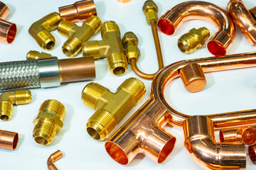 Fragment of copper pipe adapters. Connecting parts for plumbing. Background with copper plumbing elements. Copper connecting pieces on a white table. Background on theme of plumbing work.