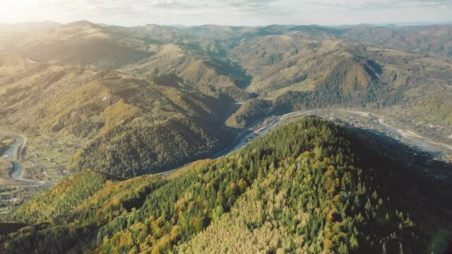 Sun over mountain ranges aerial. Pine forest at mount hills. Town at river shore. Village with fields at isolated lands. Green grass valley. Cottages at Peneda Geres National Park, Portugal, Europe
