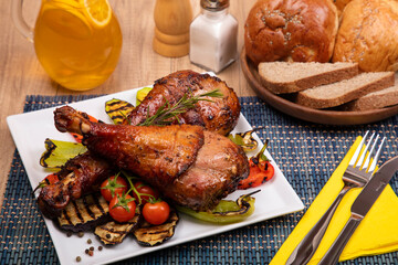 Grilled chicken with vegetable garnish served in a white plate with slice of bread, spices and juice on wooden table. Delicious dinner.