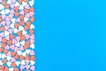 Many colorful little hearts on blue background with a copy space.