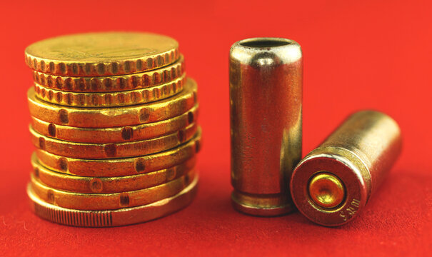 Bullet for a gun and money coins close-up photo, criminal and corruption concept