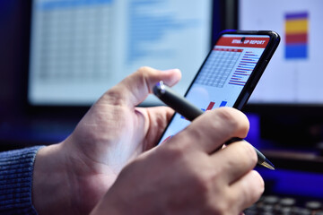 Businessman sitting in night office and using mobile phone