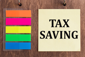 text Tex Savings on yellow note paper over wooden background. Business concept for Tax Savings Extra Money Refund.