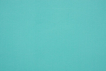 The wall of the stone building, covered with fresh blue-green plaster. The surface has texture and subtle cracks. Background.