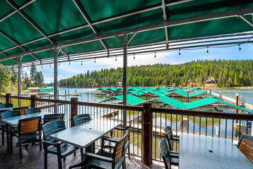 From of the lake, marina, boat slips and docks from a restaurant's empty covered patio at the Black Rock Rockford Marina in the rural mountain city of Coeur d'Alene, Idaho, USA