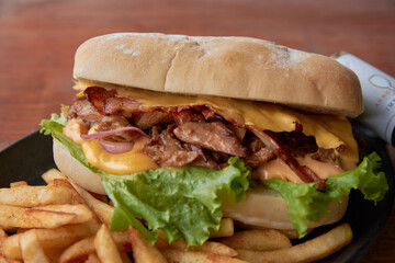 Sándwich de carne con lechuga acompañado de papas a la francesa  y salsa de queso cheddar