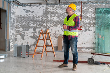 Obraz na płótnie Canvas construction worker analyzing plans during coffee break in a workshop