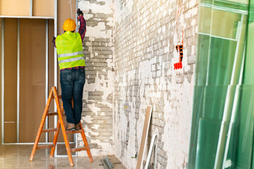 Repairman on a ladder drilling with a machine into a ceiling