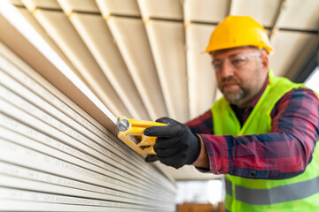 Builder in working uniform with protective helmet standing with instruments at the construction site indoors