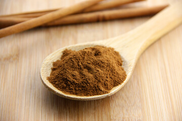 A Spoonful of Cinnamon and Cinnamon Sticks Set on a Bamboo Wooden Surface