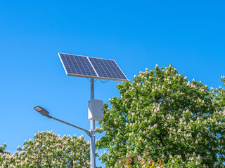 A street lamp and a solar panel against a blue sky.