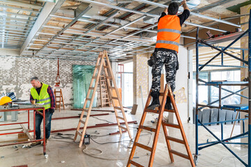 Plasterer man at work with trowel plastering the wall of interior construction site