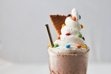 Sundae visto desde frente, con crema batida, rockets ,una bombilla y un trozo de cucurucho sobre un fondo blanco