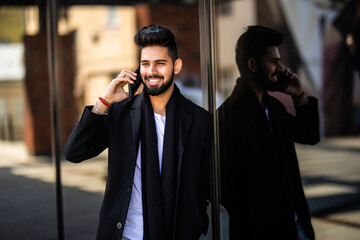 Young businessman talking on his phone outdoors near office