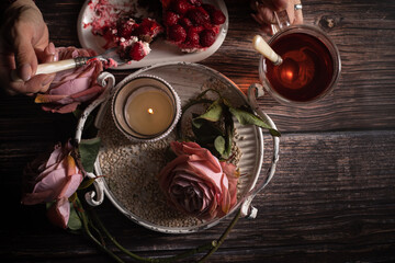 Sicht von Oben, Auf dem Tisch steht Himbeere Torte, Glas Tee,  ein Metalltablett mit Rosen, Kerzenständer, Drei Rosen im Alt Rose', , Frauen Hände sind zu sehen