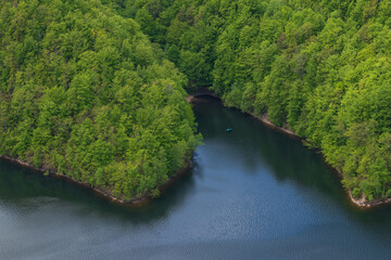 The lake in the forest photographed from above and a green boat. Aerial photography