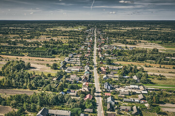 Fototapeta premium Aerial view of village surrounded by agricultural fields under blue sky idyllic view